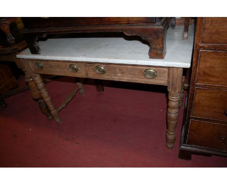 A late Victorian pitched pine and white marble topped two-drawer wash stand, having a tiled inset splashback and on ring turn