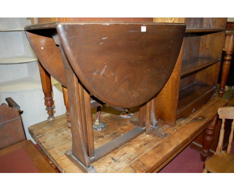 An Ercol dark elm drop flap occasional table having a gateleg action