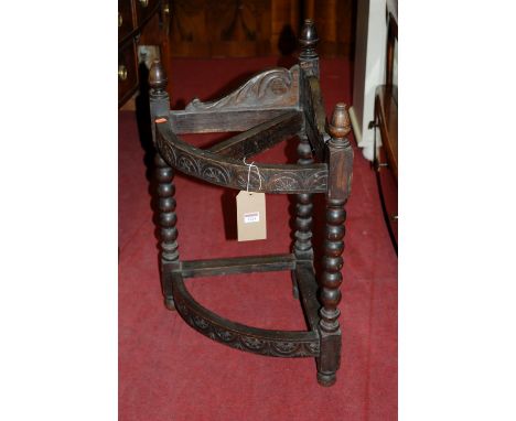 An early 20th century relief carved oak bowfront corner open two-tier stick-stand, raised on bobbin turned supports 