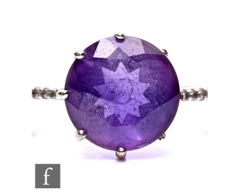 A 9ct white gold amethyst and diamond set ring, the central round cut amethyst, 1cm in size, before diamond set shoulders, ri