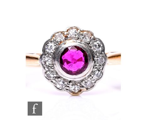 An early 20th Century 18ct ruby and diamond cluster ring, central ruby within a twelve stone diamond surround, weight 2.8g, r