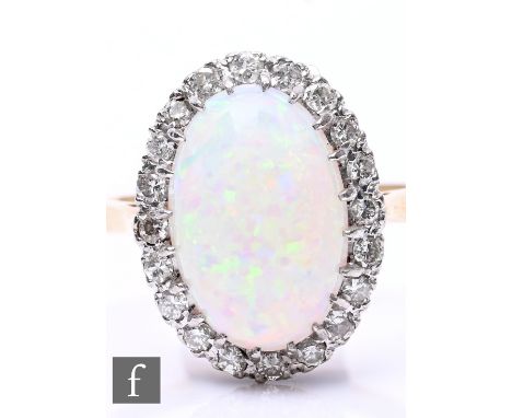 An 18ct opal and diamond cluster ring, central oval cabochon cut opal, length 14mm within a border of diamonds, weight 5g, ri