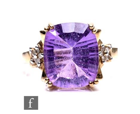 A 9ct yellow gold amethyst and diamond ring, the cushion cut amethyst 12mm x 10mm in size, flanked by three brilliant cut dia