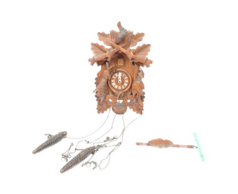 A 20th century carved wood Black Forest German cuckoo clock. The clock having hunting bugle to chapter ring surround with bir