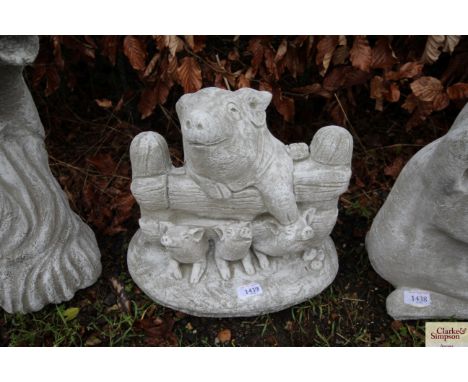 A concrete garden statue in the form of a pig over a gate with piglets