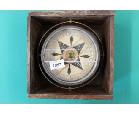 A brass marine compass mounted within wooden box