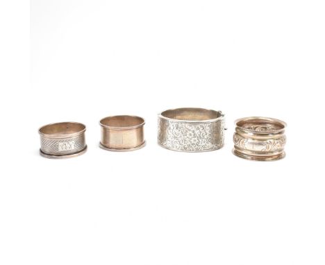 A group of three silver hallmarked napkin rings and a silver bangle bracelet. The lot to include an engine turned example (ha