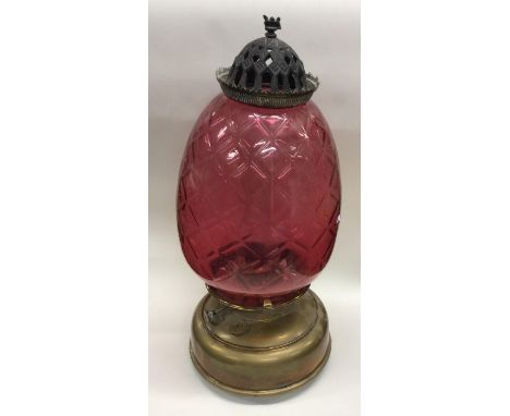 A cranberry glass and brass mounted oil lamp. Est. £70 - £80.