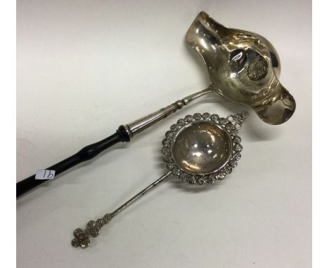 A large Georgian silver double lipped ladle together with a tea strainer. Approx. 146 grams. Est. £25 - £35.