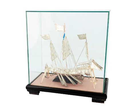 A Chinese metalware model of a junk,in full sail and with eight oars, in a fitted glass-covered case, height of case 28.5cm