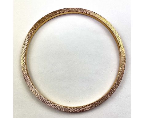 A 9ct hallmarked gold engine turned hollow bangle, Birmingham 1929, internal diameter 70mm, weight 6.9g.Condition report: Thi