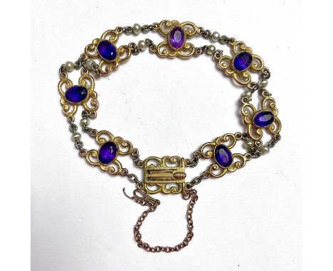 An attractive Edwardian 15ct bi-colour gold amethyst set bracelet, the seven scroll links each set with an oval cut stone eac