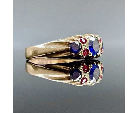 An Edwardian 9ct gold ruby and saphire ring seven stone, the central sapphire measures 0.33ct spread and flanked by two small