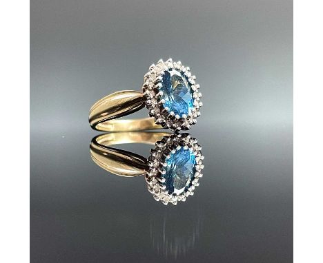 A modern 9ct hallmarked gold blue topaz and tiny diamond set cluster ring, the oval cut topaz measures 0.75ct approx, size J/