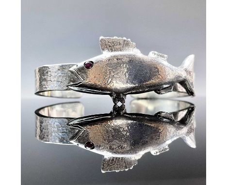 A contemporary .999 fine silver heavy bangle, applied with and titled Newlyn Seabass, with a ruby set eye, weight 119.5g.