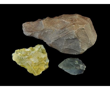 Palaeolithic to Neolithic, 350000-4000 BC. A group of artefacts comprising: a Palaeolithic bifacial handaxe in a purple basa