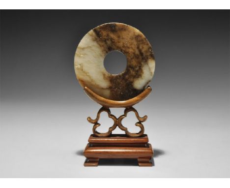  3rd millennium BC. A carved nephrite jade pi ceremonial ring, mounted on a modern wooden stand. See Rawson, J. Chinese Jade: