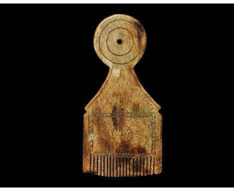  9th-11th century AD. A carved bone comb formed as a discoid handle with concentric incised circles and central hole, flared 