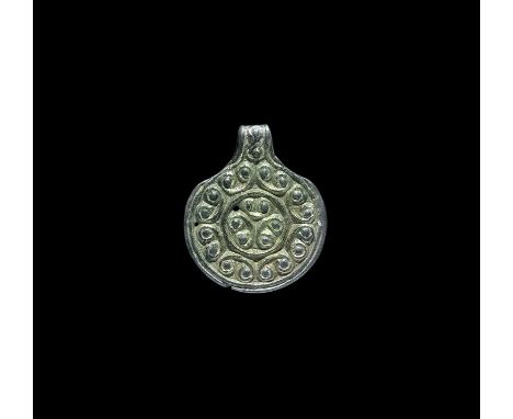  10th-12th century AD. A silver-gilt pendant with concentric bands of c-scrolls, integral loop. Cf. Arbman, H. Birka I: Die G