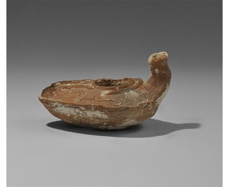  7th-10th century AD. A terracotta slipper-shaped lamp with large filler hole, narrow discuss and channel, chamfered shoulder