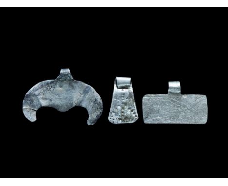  9th-12th century AD. A mixed group of silver pendants comprising: one lunate with scrolled loop; one rectangular with incise