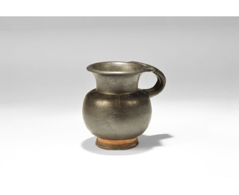  4th century BC. A black glazed ceramic vessel with vertically ribbed bulbous body, low pedestal base, flared neck with chamf
