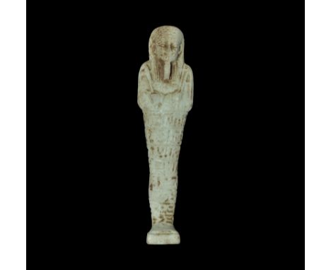  Late Period, 664-332 BC. A pale green finely modelled glazed composition shabti with tripartite wig, false beard, agricultur