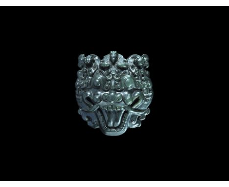  19th-20th century AD. A dark spinach-green jade plaque with hollow reverse and transverse bar, grotesque facing mask with op