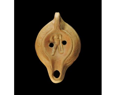  1st-3rd century AD. A discoid terracotta lamp with short nozzle, loop handle to the rear; the discus with two round holes an