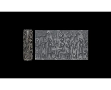  14th-10th century BC. A carved bitumen cylinder seal with frieze of figures with wine-jars, cups and strainers; accompanied 