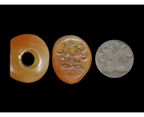  4th-6th century AD. A carnelian annular stamp seal with one flat face, intaglio design of beast-heads beneath a star; suppli