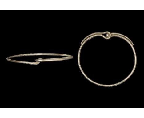  5th century AD. A massive silver neck torc with ends bent back to form the catchment loop; ends tapering along the edge of t