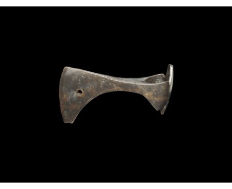  10th-12th century AD. A hand-forged iron axehead with slightly curved edge, notched chin, central hole, extensions to the re