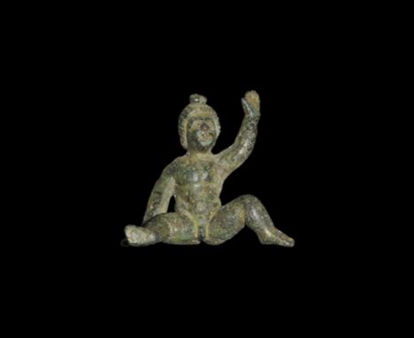  1st-2nd century AD. A bronze figurine of a putto modelled in the round with legs spread, one hand extended upwards and the o