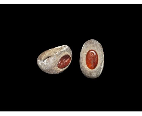  3rd century AD. A lentoid-section silver ring with broad plaque and inset carnelian intaglio of a winged Victory standing ro