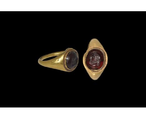  1st century AD. A round-section hollow-formed gold hoop with flared shoulders, flat plaque with cell, inset garnet(?) caboch