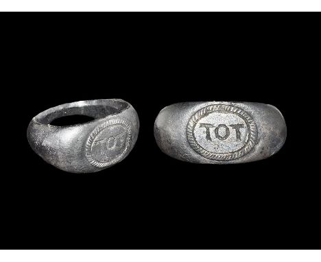  2nd-4th century AD. A silver D-section hoop and discoid plaque with ropework border enclosing the amuletic inscription 'TOT'