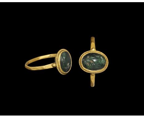  3rd century AD. A narrow gold facetted hoop with granules to the shoulders, pie-dish bezel with beaded wire collar, inset gl