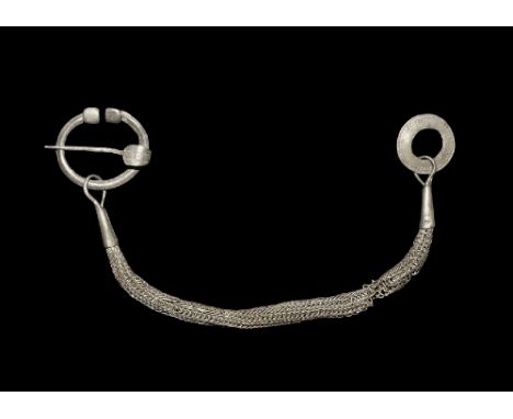  12th century AD. A D-section silver penannular brooch with clubbed ends, surmounted by rectangular studs, its pin formed as 