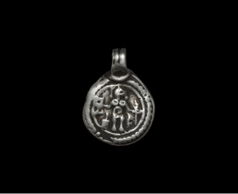  8th-9th century AD. A flat-section silver disc pendant with applied ribbed loop, band of pellets between borders enclosing a