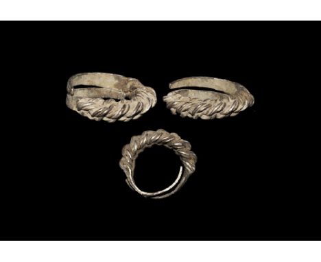  10th-12th century AD. A silver penannular hoop formed with butted tapering finials, median section of twisted wire in three 