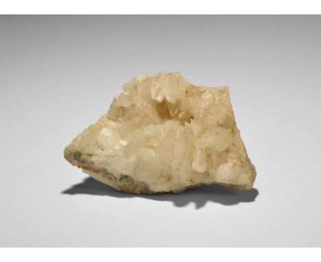  . A group of dogtooth (scalenohedral) calcite crystals on a matrix of limestone, with tiny overgrowths of pyrite(?) on the c