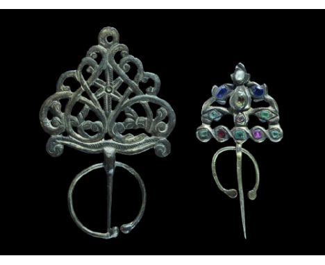  19th century AD. A mixed pair of silver brooches comprising: a tapering pin with openwork D-shaped plaque, tendril and leaf 