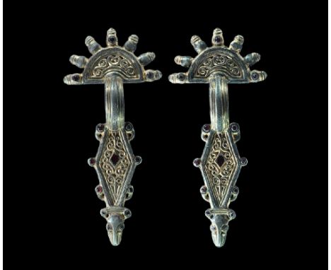  Later 5th-6th century AD. A matched pair of parcel-gilt silver bow brooches, each comprising: a D-shaped headplate with rais