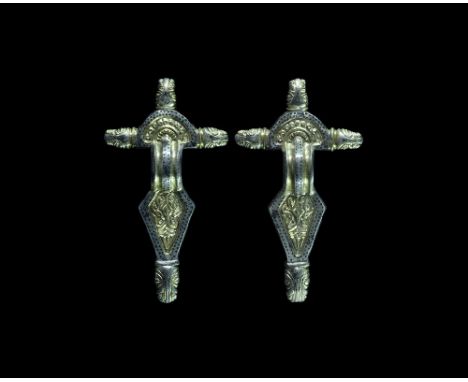 Early 6th century AD. A matched pair of parcel-gilt silver radiate-headed bow brooches, each with a D-shaped headplate and t