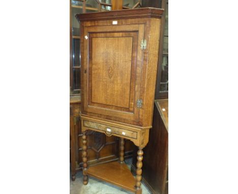 A 19th century oak corner cupboard, having a single door with central inlaid shell motif, on associated stand, with bobbin-tu