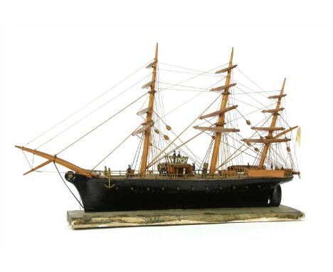 A wooden and ebonised model of a sailing ship, late 19th century, set with painted figures and flying the white ensign, on a 