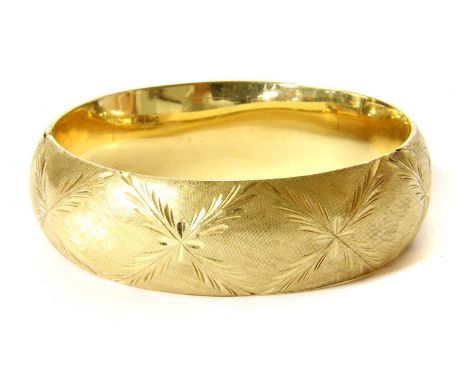 A hollow hinged bangle, with cross hatch texture and hand engraved foliate cross motifs, to push piece and bar fitting, teste