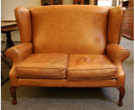 A modern tan brown leather wing back two seater sofa,136cm wide, 76cm deep and 108cm high