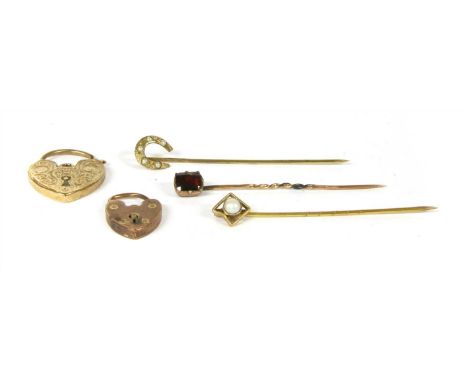 A flat cut garnet stick pin, a seed pearl horseshoe stick pin, a pearl stick pin, and two heart shaped padlock clasps, all te